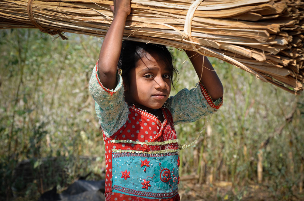 Child carrying a bundle of wood