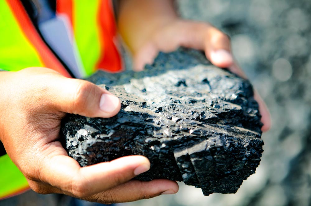 A lump of coal held by someone wearing a reflective vest.